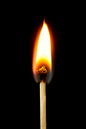 Closeup of burning match, isolated on black background.  Great detail.