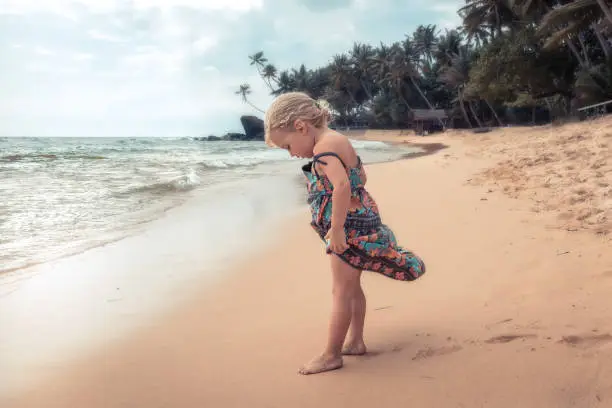 Beautiful child girl playing on beach during summer holidays concept for carefree childhood travel lifestyle