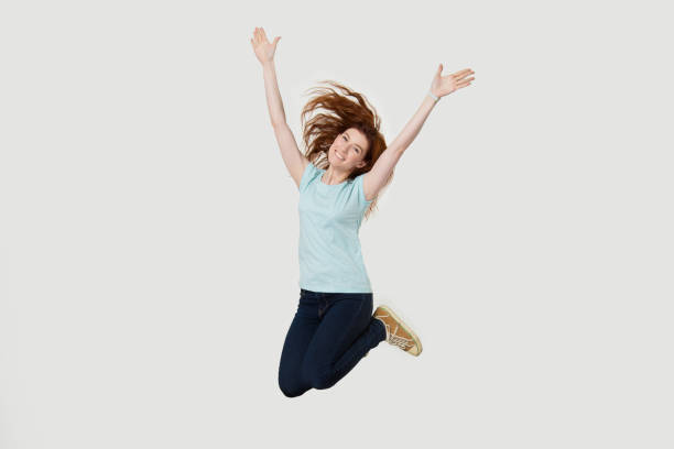 istock Excited redhead girl have fun jumping with hands up 1157002185