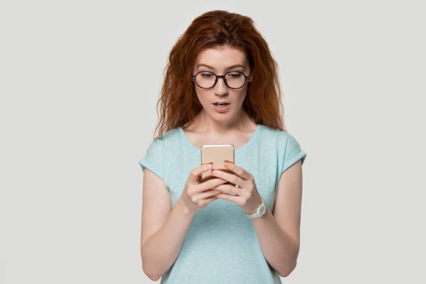 istock Surprised redhead girl holding smartphone read unexpected message 1157002193
