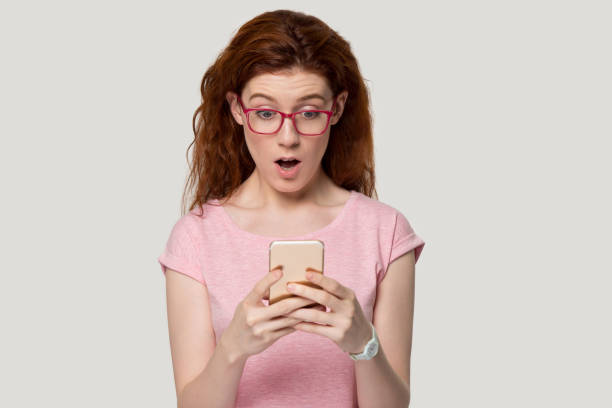 istock Surprised redhead girl hold cellphone get unexpected message 1157002246