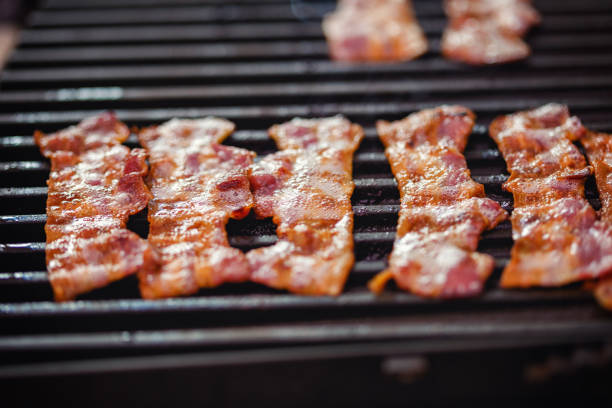 Slice of bacon frying on the barbecue grill