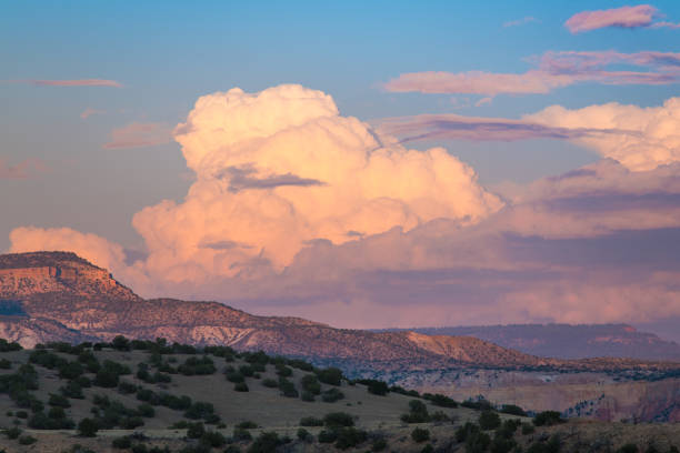 sunset pinta nubes cúmulos y cabezas de trueno en colores suaves de rosa, púrpura y melocotón sobre un colorido paisaje desértico - santa fe new mexico fotografías e imágenes de stock