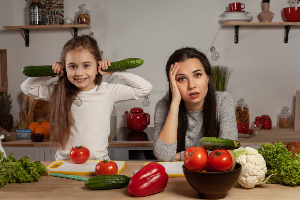 madre e sua figlia stanno facendo un'insalata di verdure e si divertono in cucina - mother emotional stress exhaustion cooking foto e immagini stock