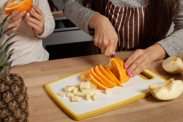 istock Mother and her daughter are doing a fruit cutting and having fun at the kitchen 1157015846