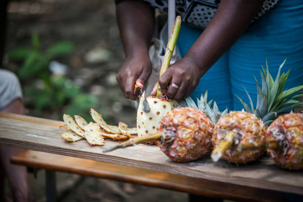 istock Woman cutting pineapples in Haiti on a long table 1157018402