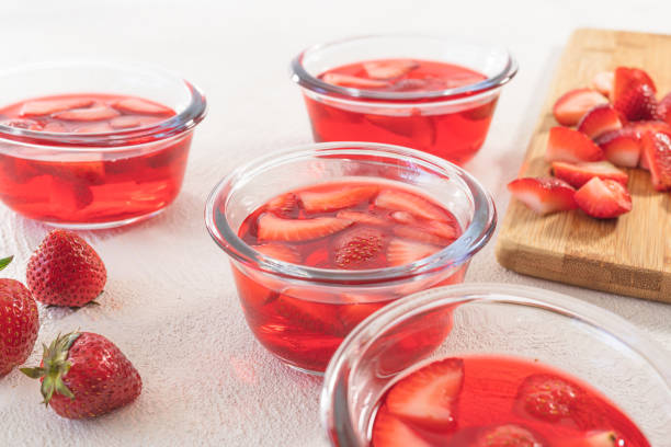 geléia de morango em bacias de vidro, morangos cortadas em uma placa de desbastamento, fim acima, no fundo branco - gelatin dessert - fotografias e filmes do acervo