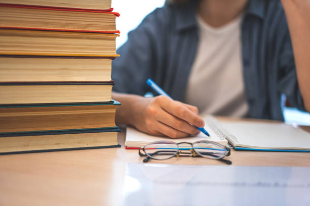 istock Young student sitting at desk in home studying and reading, doing homework and lesson practice preparing exam to entrance, education concept. 1157020291