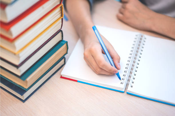 istock Young student sitting at desk in home studying and reading, doing homework and lesson practice preparing exam to entrance, education concept. 1157020300