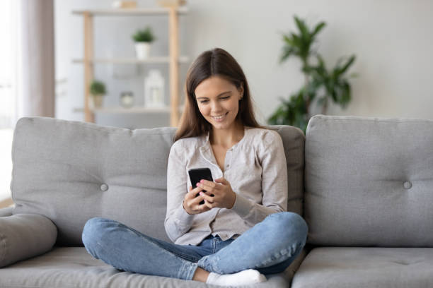 istock Smiling teenager sit on couch use smartphone texting message 1157025878