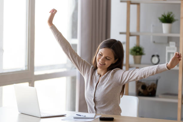 istock Smiling young woman stretching working at laptop 1157025942