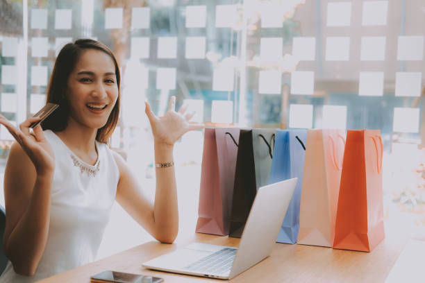 istock woman using computer & credit card for online payment with shopping bag on table. consumerism lifestyle concept 1157026295