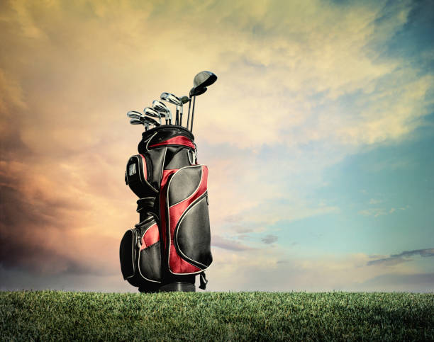 Red and black golf bag with clubs on grass against dramatic clouds