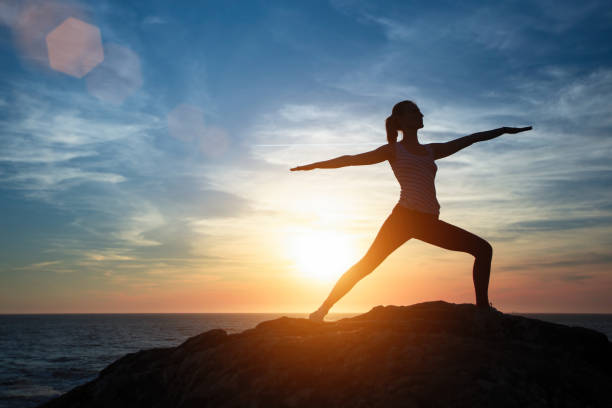 istock Silhouette young woman practicing yoga on the sunset beach. Tranquility and concentration. 1157027746