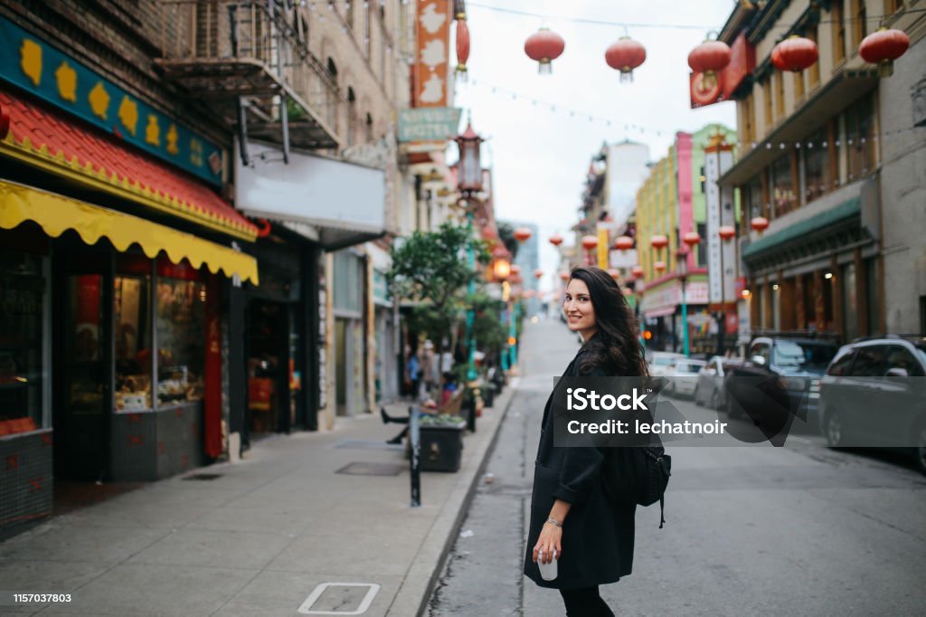 Solo traveler in Chinatown of San Francisco, California Young woman walking down the Chinatown district in San Francisco, California. She is wearing casual clothing, carrying a cup of coffee to go, enjoying the vibrant and famous Chinese district. San Francisco - California Stock Photo