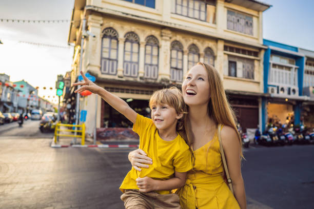 Mom and son tourists on the Street in the Portugese style Romani in Phuket Town. Also called Chinatown or the old town. Traveling with kids concept Mom and son tourists on the Street in the Portugese style Romani in Phuket Town. Also called Chinatown or the old town. Traveling with kids concept. driveway colonial style house residential structure stock pictures, royalty-free photos & images