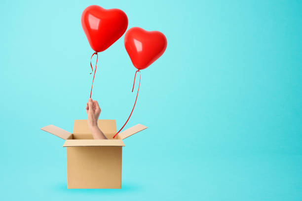 istock A hand from a cardboard box holds a red heart-shaped balloon 1157039343