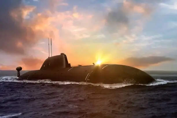 Naval submarine at sea surface during sunset under cloudy sky