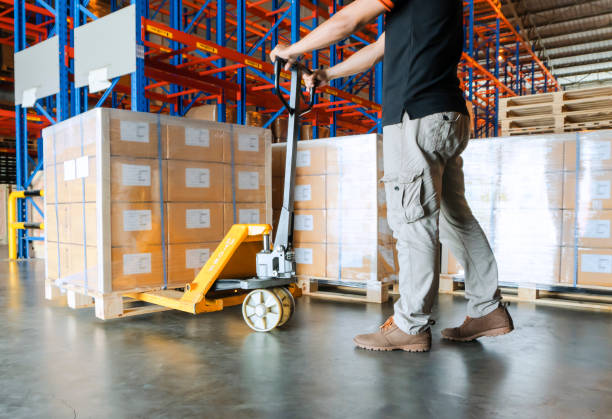istock Warehouse worker is working with hand pallet truck and cargo pallet 1157049069