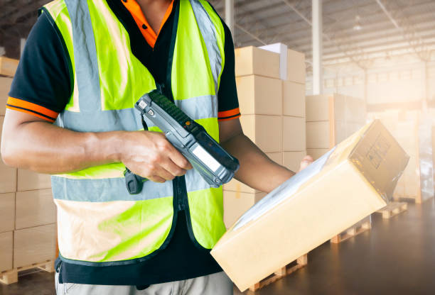 Warehouse worker holding barcode scanner is scanning with parcel box. Warehouse worker is working with cargo in warehouse. Barcode label  stock pictures, royalty-free photos & images