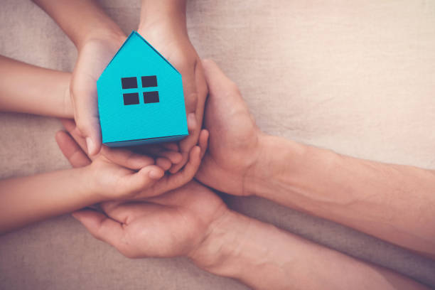 adult and child hands holding blue paper house for family home and homeless shelter concept - savings finance education mortgage imagens e fotografias de stock