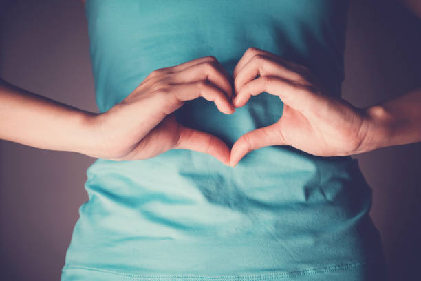vrouw handen maken van een hart vorm op haar buik, gezonde darm degestion, probiotica voor darmgezondheid - buik stockfoto's en -beelden