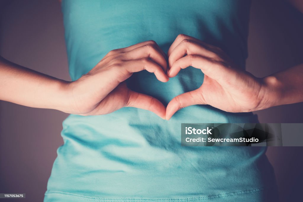 Woman hands making a heart shape on her stomach, healthy bowel degestion, probiotics  for gut health Intestine Stock Photo