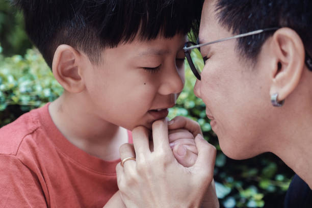 Young Asian boy praying with his mother in the park outdoors, family pray Young Asian boy praying with his mother in the park outdoors, family pray praying child christianity family stock pictures, royalty-free photos & images