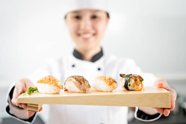 chef präsentiert einen teller mit lachssushi - sushi japanese culture food domestic kitchen stock-fotos und bilder