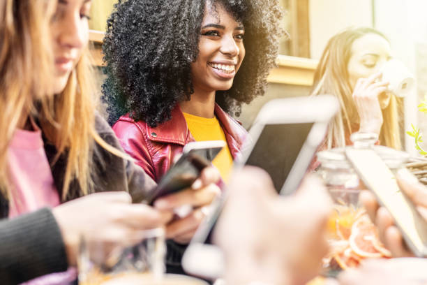istock Group of friend talking sitting on a coffee table while using smartp phones together. 1157056516