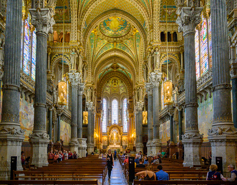 People roaming around inside the Basilica Notre Dame in Lyon at visit hours during the day.