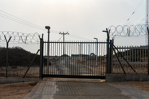 Barbed wire fence block the way. gate to a closed area. Automatic metal gate