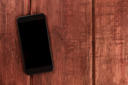 A phone, shot from above on a dark wooden background, a mockup of a blank screen with a place for text