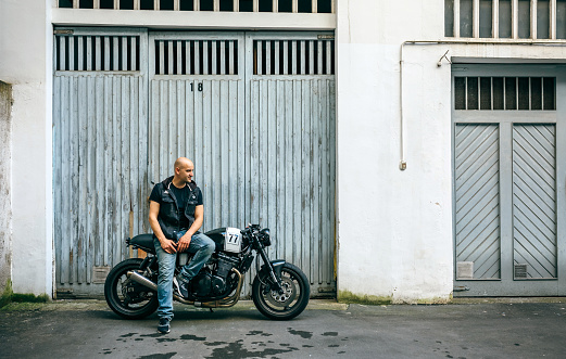 Biker posing with a custom motorcycle in front of the garage door