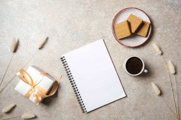 istock Flat lay of blank paper notebook with copy space mock up. Top view home office desk workspace decorated with dry flowers, gift box, coffee cup and cookies. Beauty blogger, minimal women desk concept. 1157076686