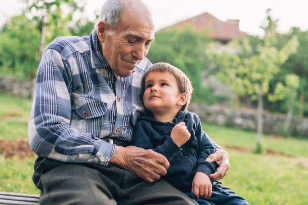 istock Grandfather sitting on a bench and embracing his cute grandson. 1157080607