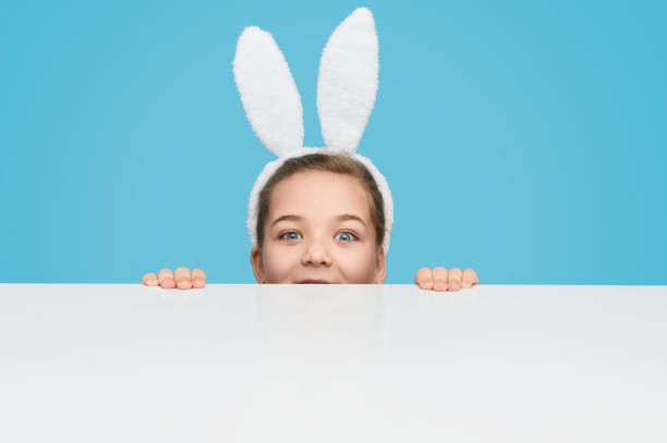 istock Charming girl in bunny ears hiding behind table 1157085356