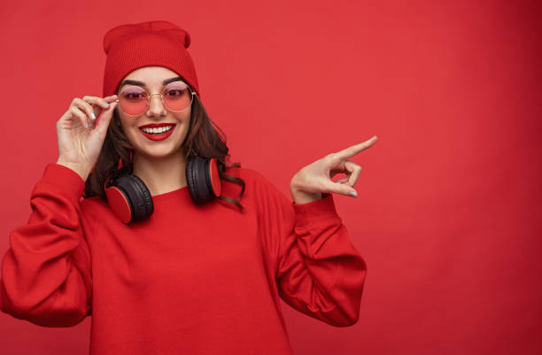 Stylish girl in red outfit pointing away stock photo