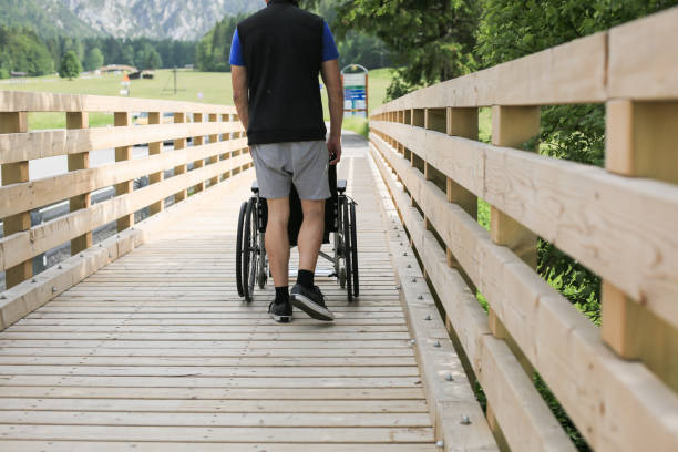 istock Assistant and disabled young man on a wheelchair 1157085547