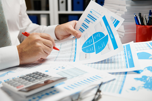 Businessman working and calculating, reads and writes reports. Office employee, table closeup. Business financial accounting concept.