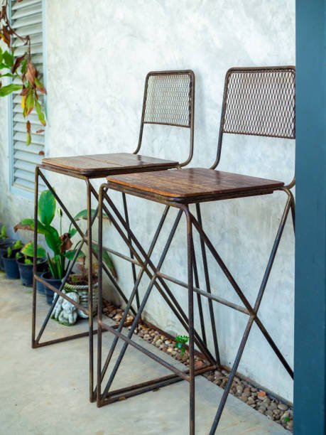 Two iron and wooden bar stools on cement wall background