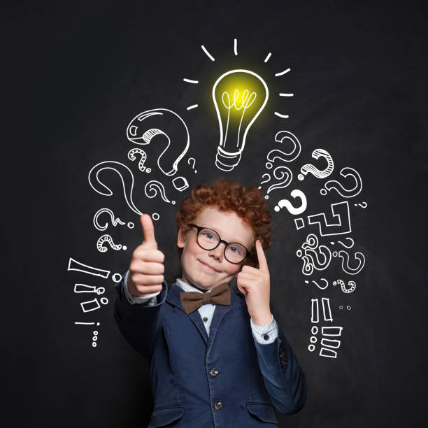 istock Smart kid student and lightbulb on blackboard background. Happy child showing thumb up. Brainstorming and idea concept 1157087254