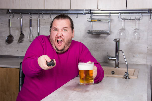 sadness and despair. alcoholism. the man is at home. - remote fat overweight dieting imagens e fotografias de stock