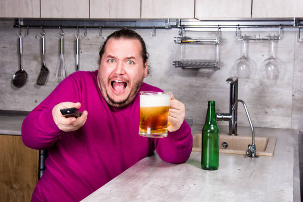 sadness and despair. alcoholism. the man is at home. - remote fat overweight dieting imagens e fotografias de stock