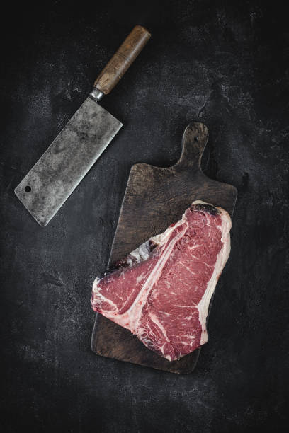 raw dry aged t-bone steak on vintage chopping board with meat cleaver - veal t bone steak raw steak imagens e fotografias de stock