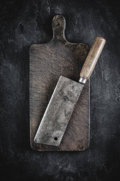 istock Butcher Meat Cleaver and Rustic Wood Chopping Board on Dark Background 1157088194