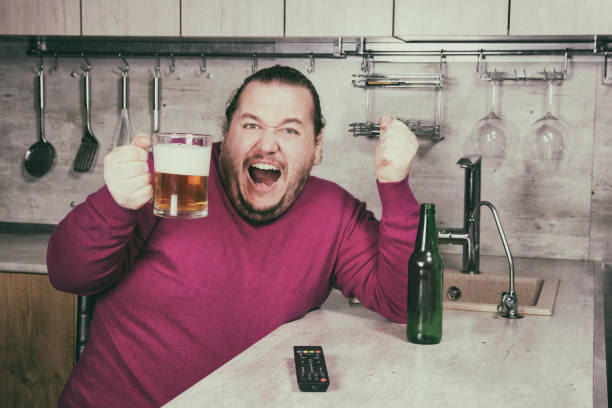 sadness and despair. alcoholism. the man is at home. - remote fat overweight dieting imagens e fotografias de stock