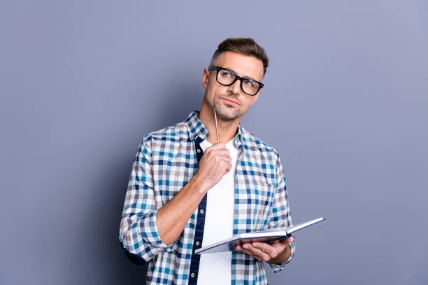 istock Close up photo handsome he him his guy pen chin hands arms hold notebook making notes carefully author have inspiration clever smart wear specs casual plaid checkered shirt isolated grey background 1157092783