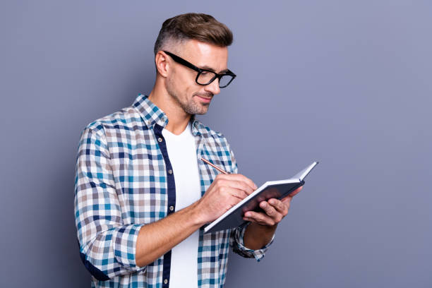 istock Close up photo handsome he him his guy hands arms hold notebook making notes author have inspiration clever smart creative ideas wear specs casual plaid checkered shirt isolated grey background 1157092964