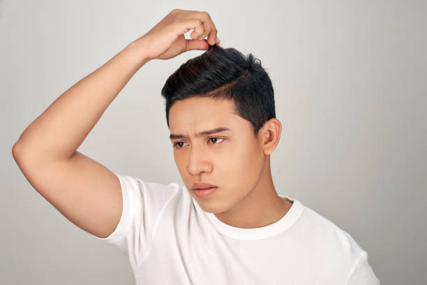 istock puzzled scared sad nervous depressed asian man with beard touching his hair, having problems with hair, isolated white background 1157094379